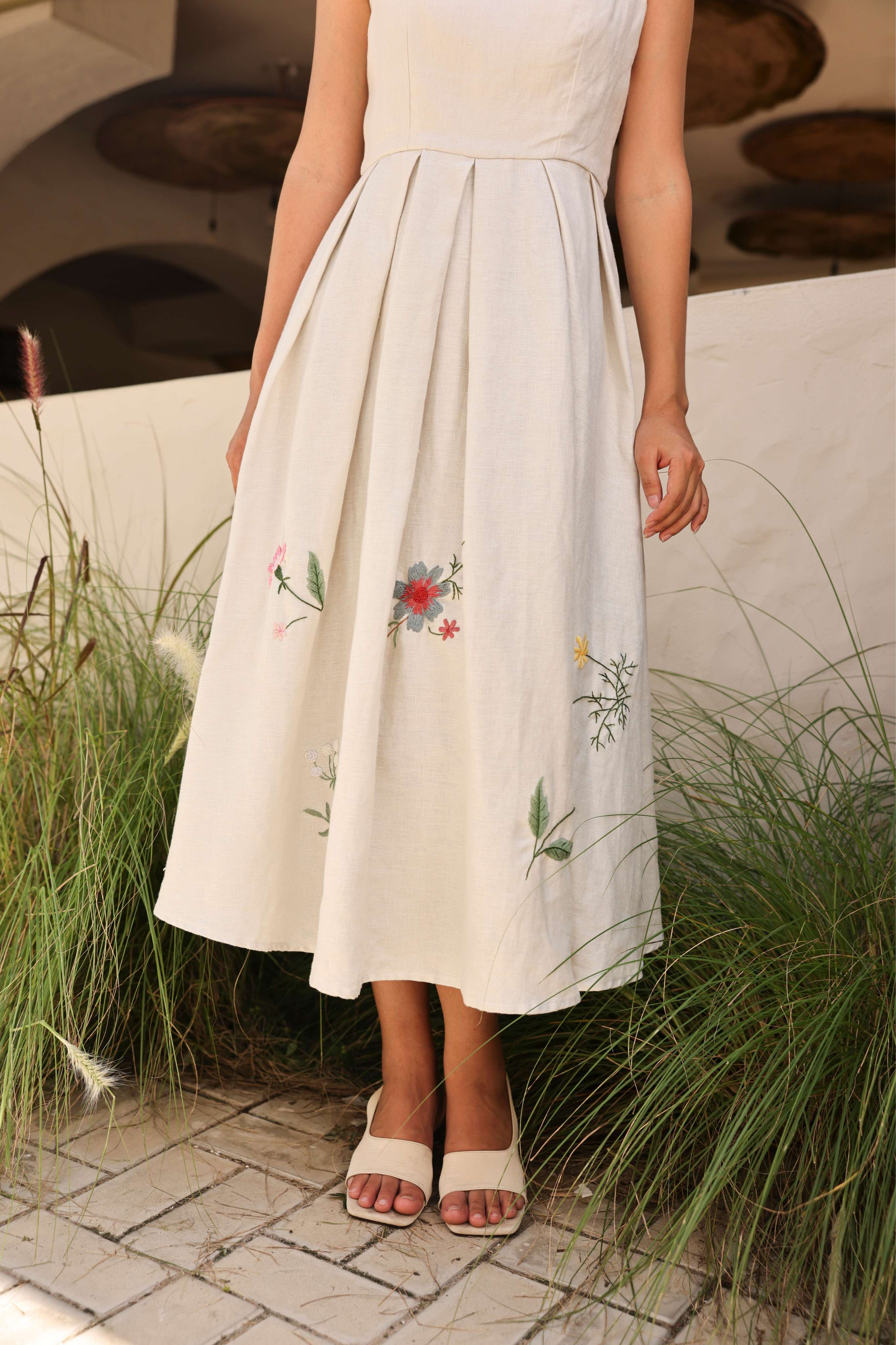 Woman wearing a dress with floral embroidery standing outdoors.