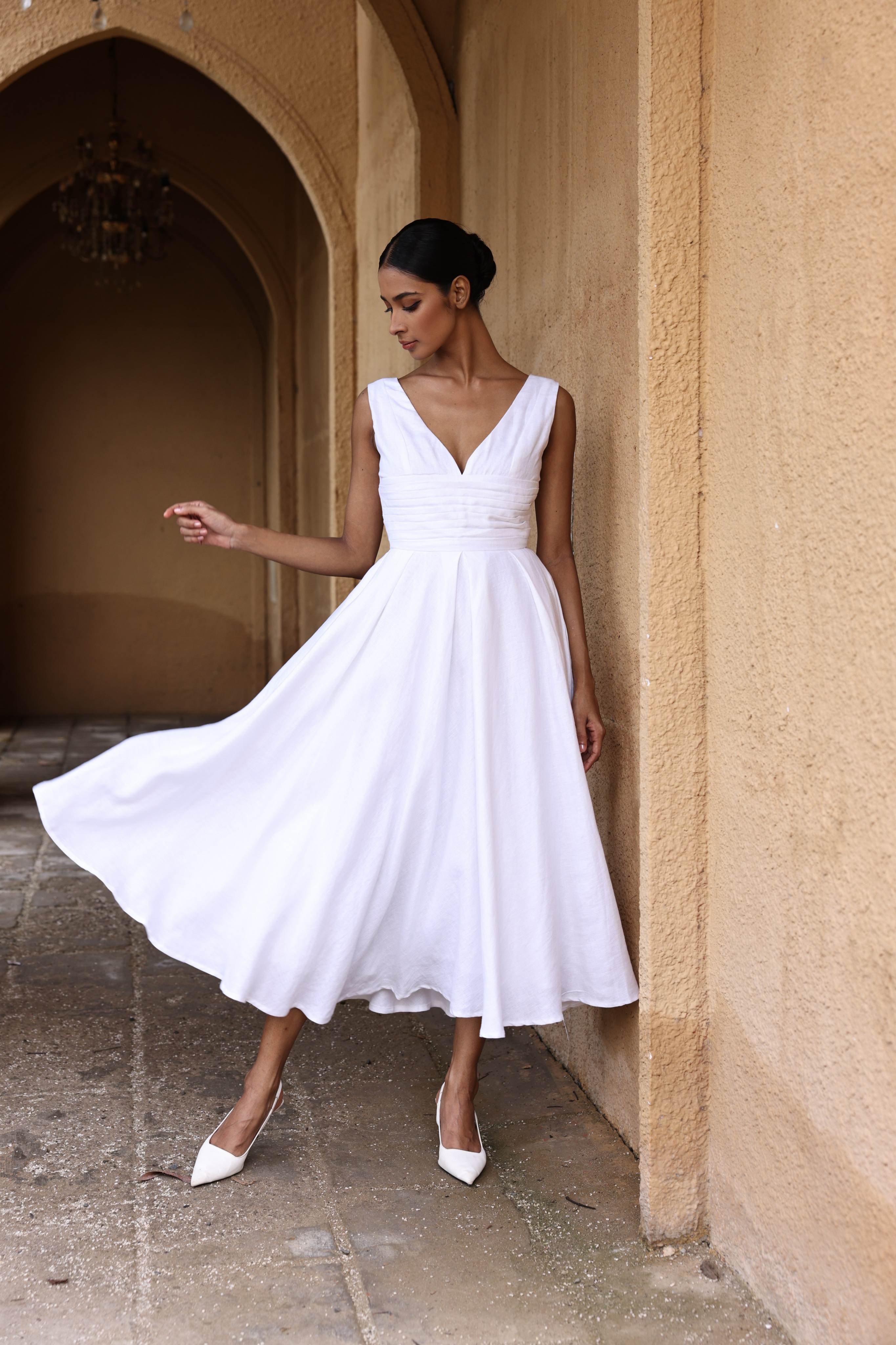 Woman in a white dress standing in an arched doorway.