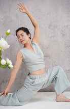Woman in a wrap top against a gray background with white flowers on the left.