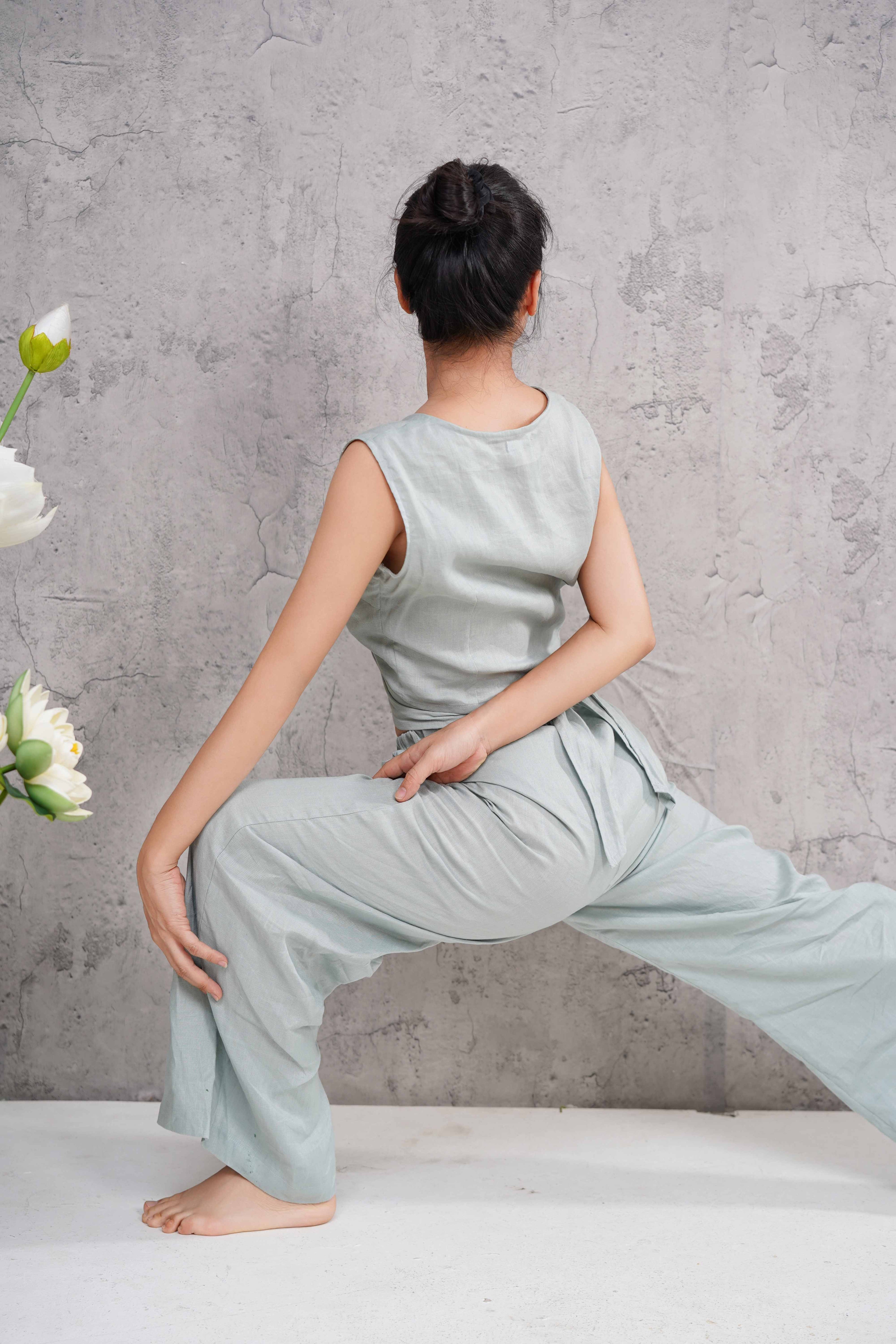 Person wearing a light blue outfit sitting against a gray wall with flowers on a white surface.