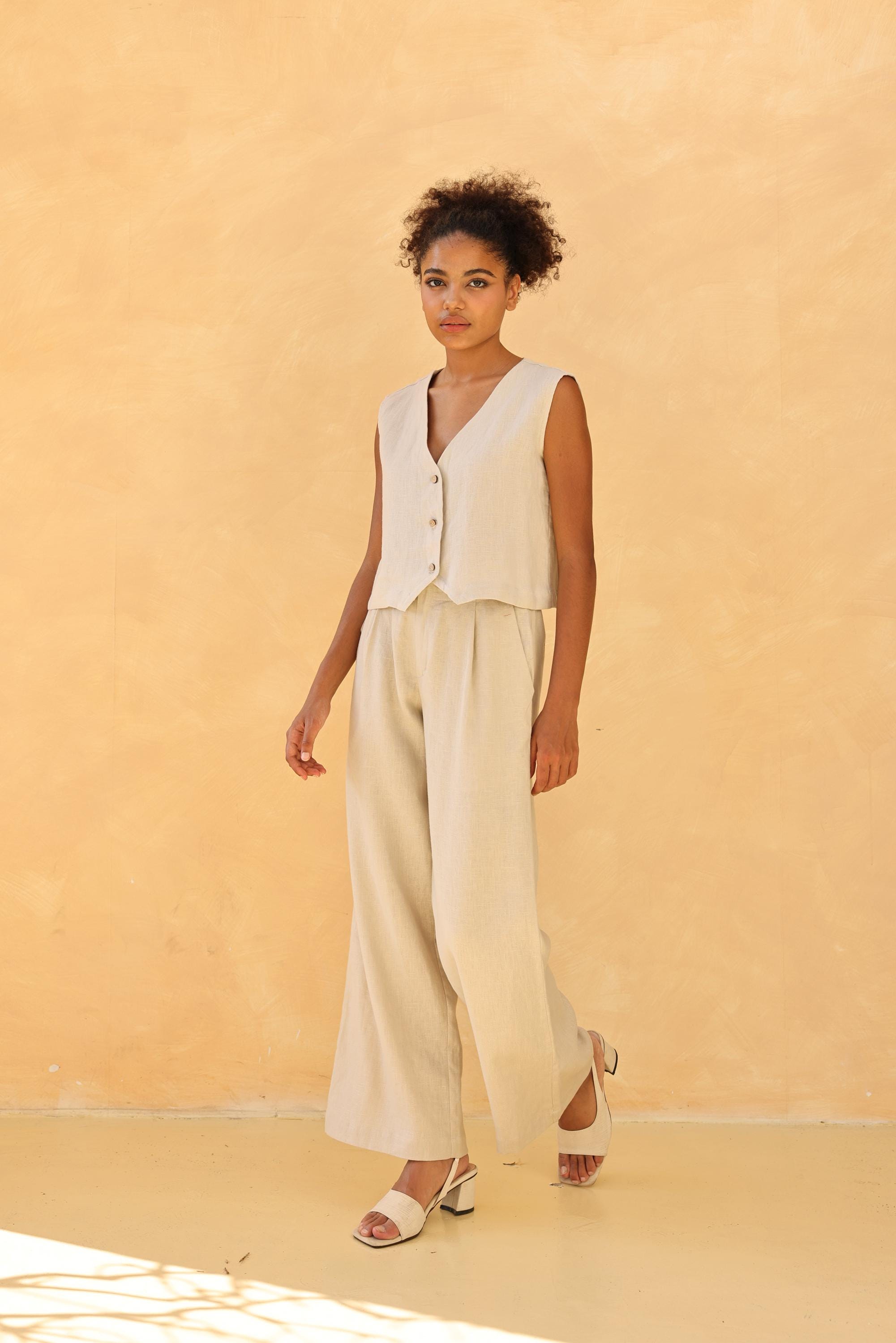 Woman wearing a cream-colored sleeveless top and wide-leg pants against a beige background