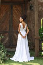 Woman in a white dress standing in front of a wooden door.