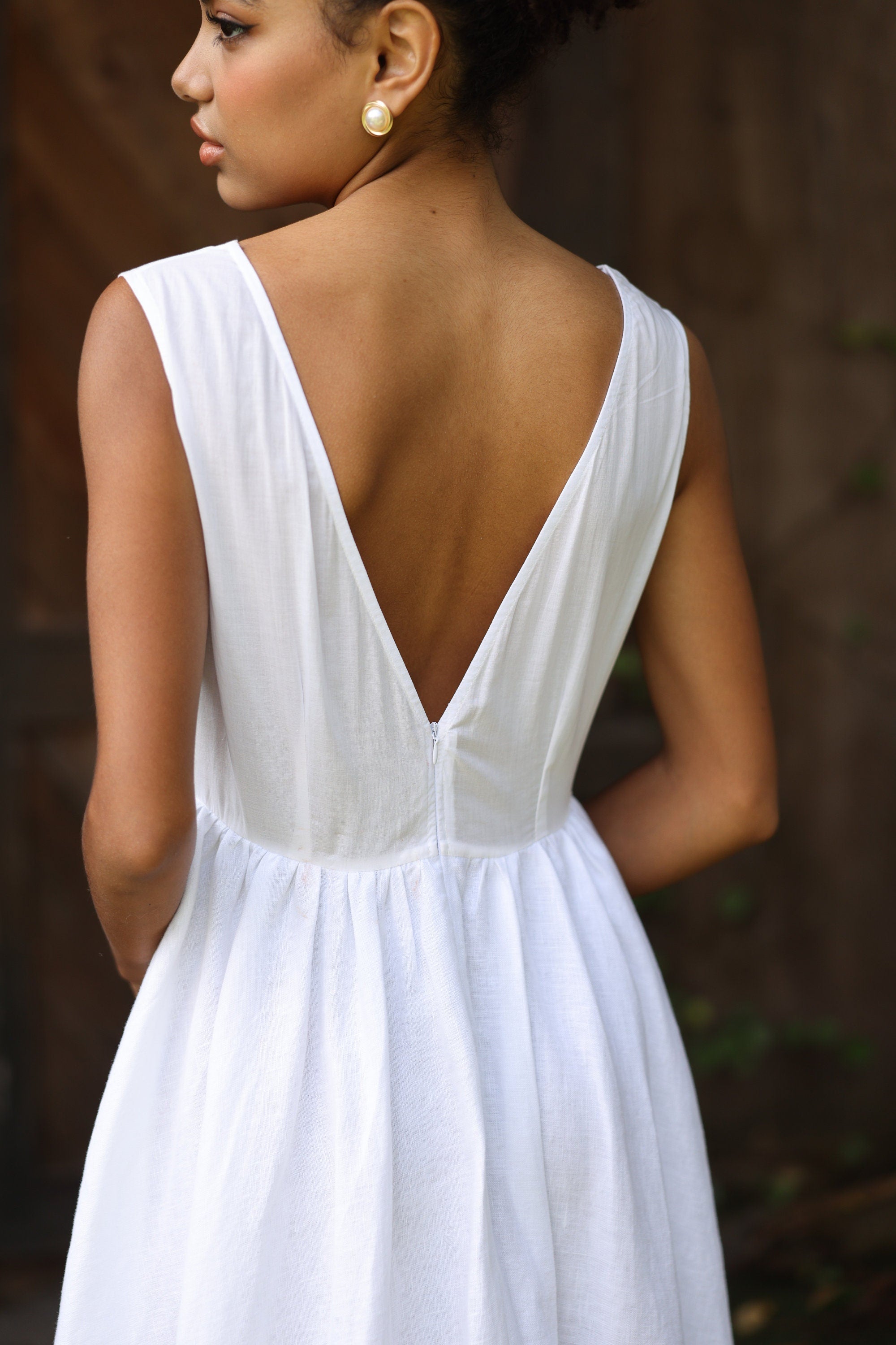 Woman wearing a white dress with a deep backless design against a blurred background