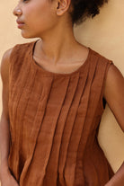 Woman wearing a brown sleeveless top against a beige background