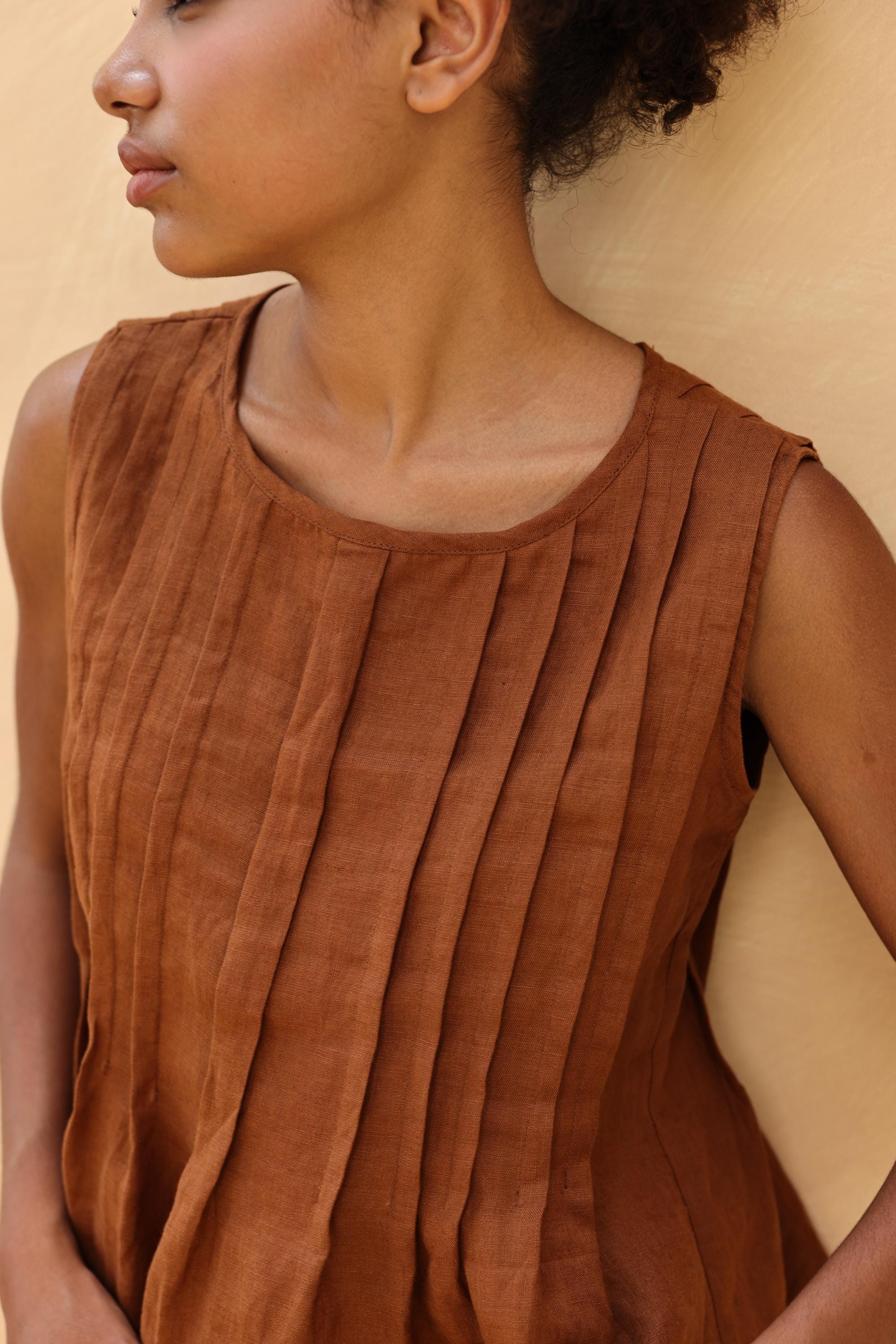 Woman wearing a brown sleeveless top against a beige background