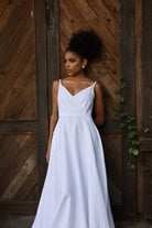Woman in a white dress standing against a wooden wall with a rustic background