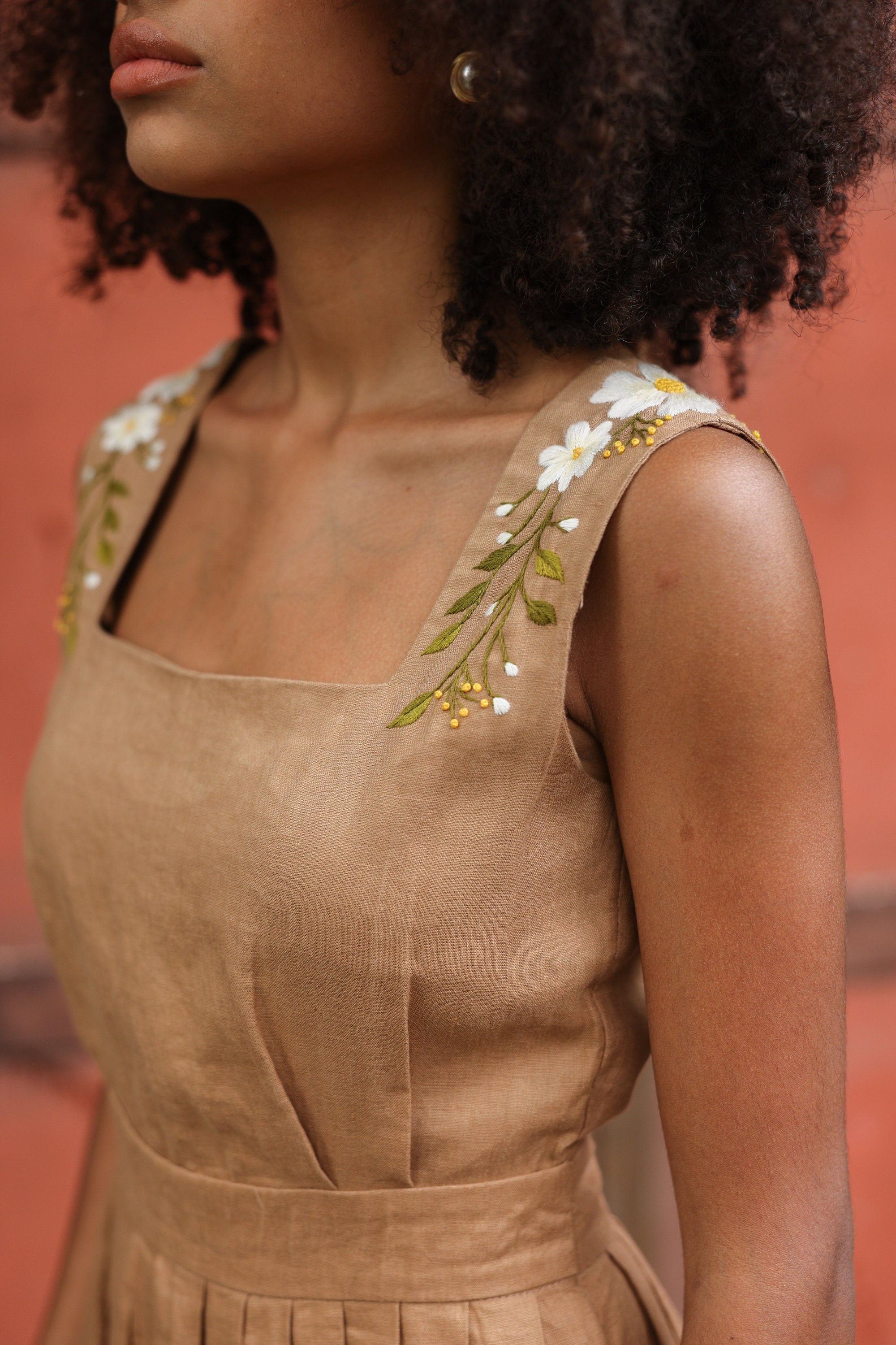 Woman wearing a beige dress with floral embroidery on a blurred background