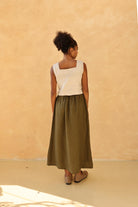 Woman wearing a top and green skirt against a beige wall