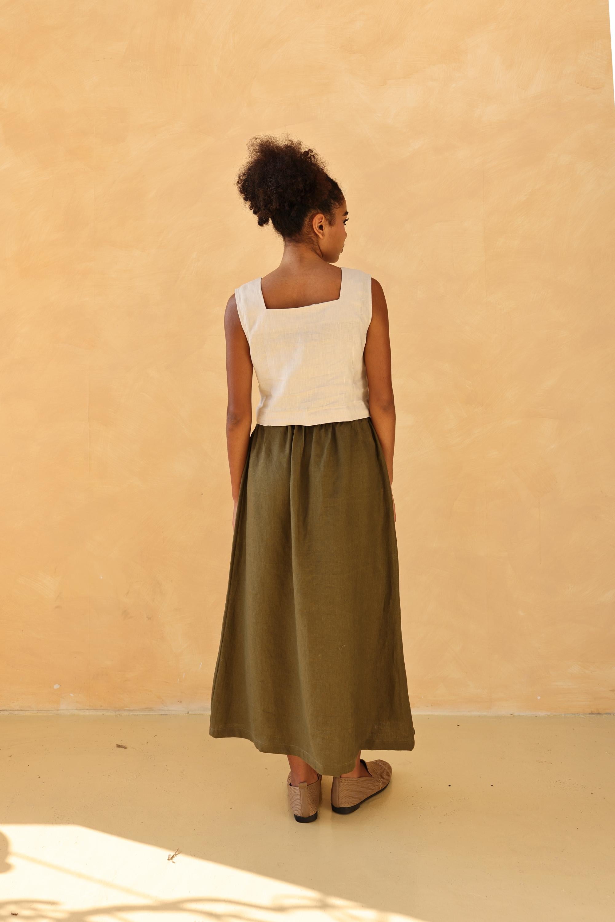 Woman wearing a top and green skirt against a beige wall