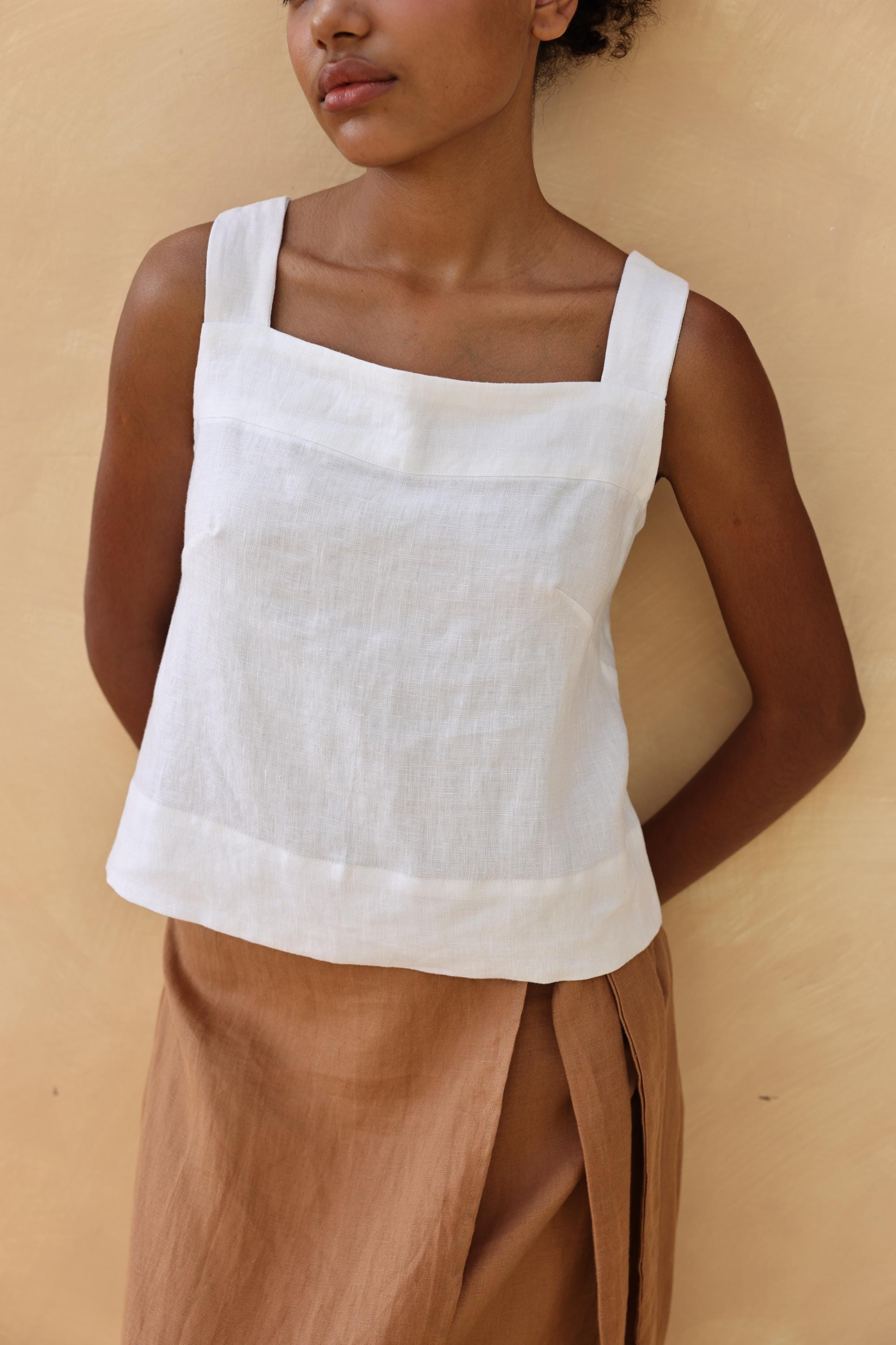 Person wearing a white top and brown skirt against a beige background