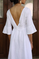 White dress with open back and ruffled sleeves worn by a person.