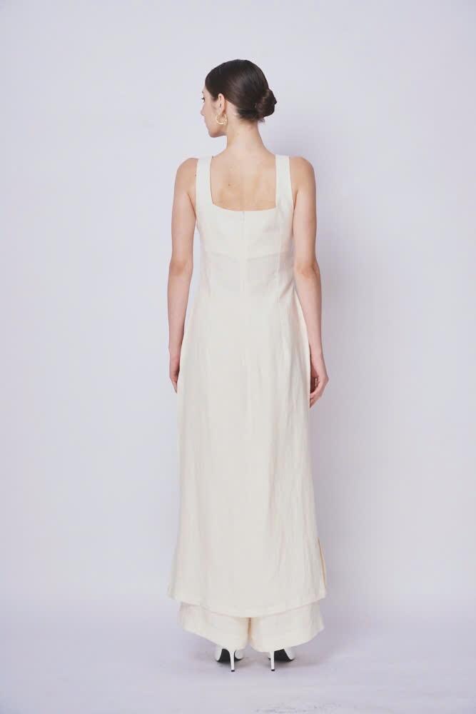 Woman wearing a long, light-colored dress against a white background