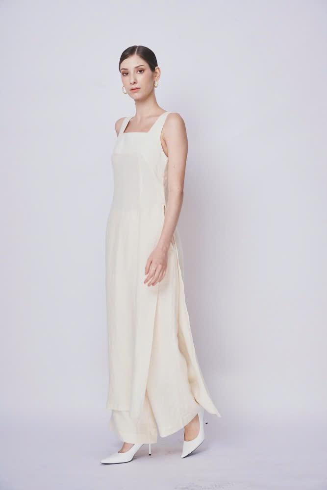 Woman wearing a long, light-colored dress against a plain background