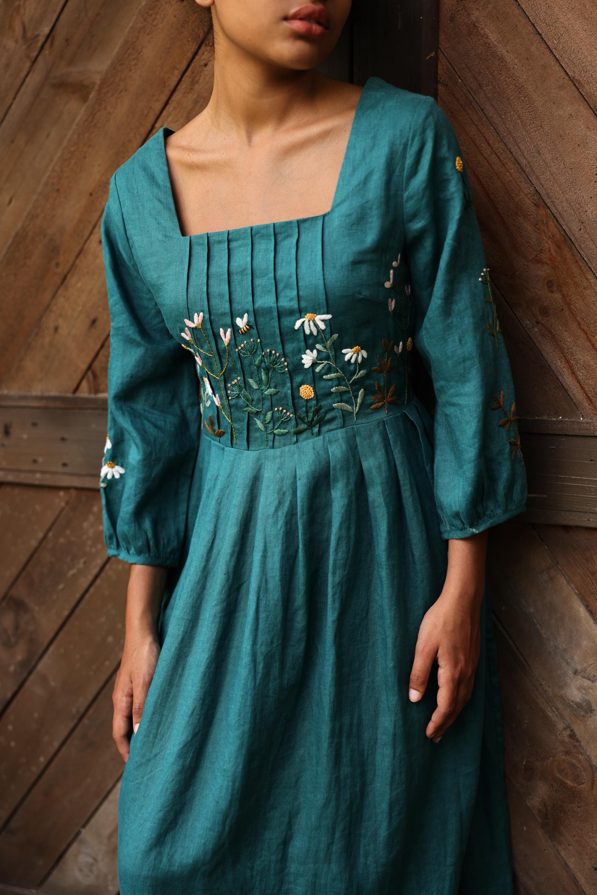 Teal dress with floral embroidery on a wooden background