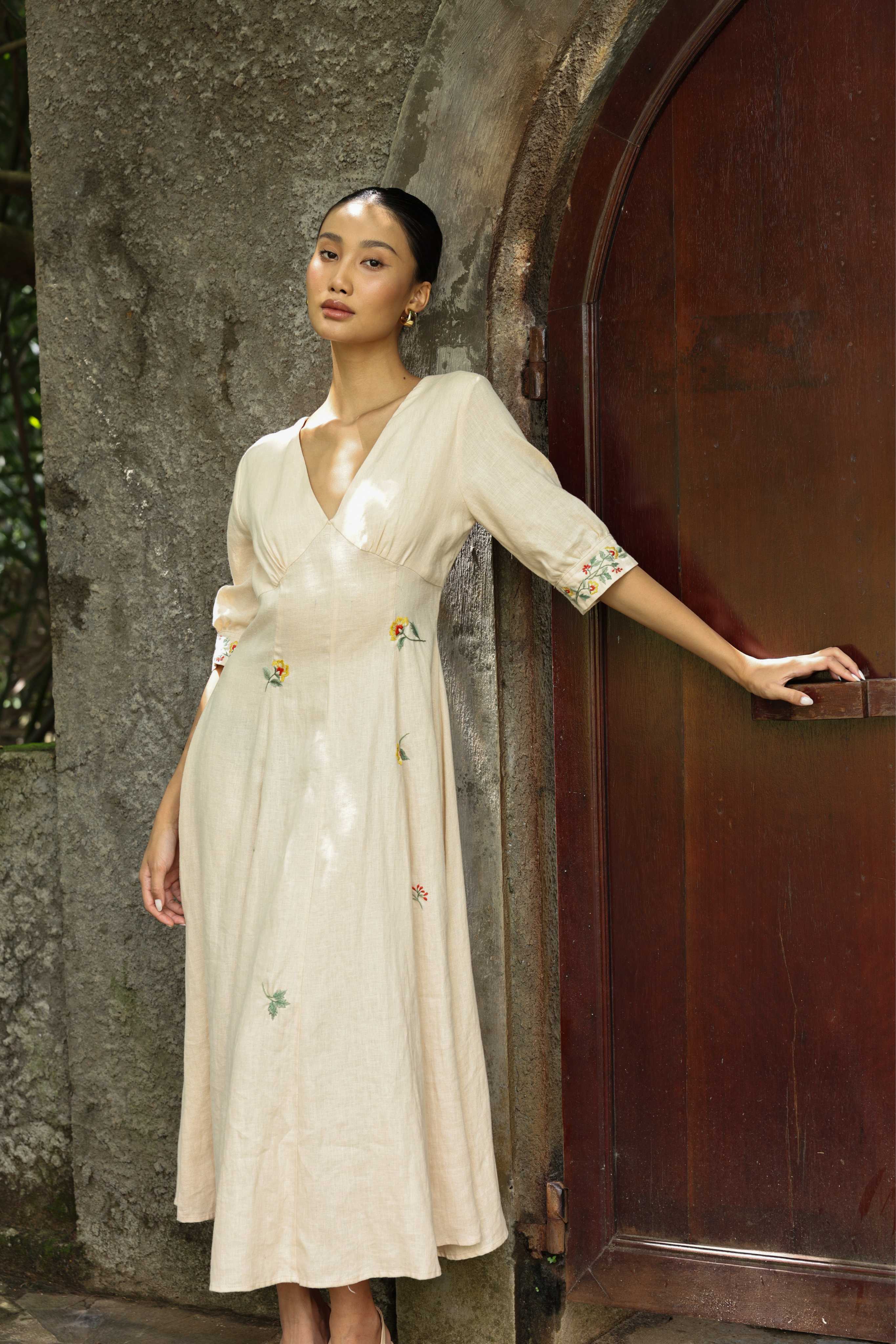 Woman in a dress standing next to a wooden door.