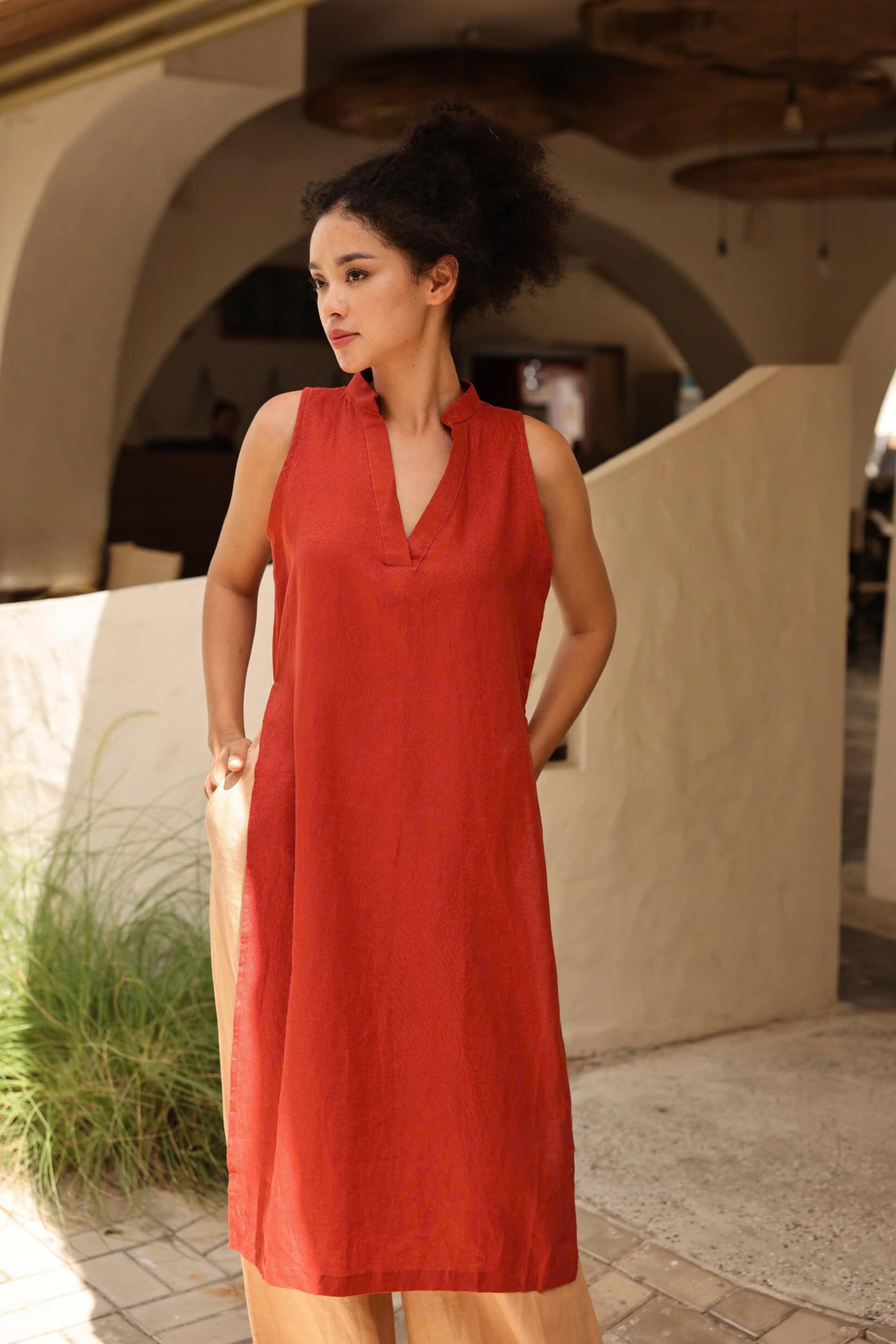 Woman wearing a red dress standing outdoors with architectural elements in the background