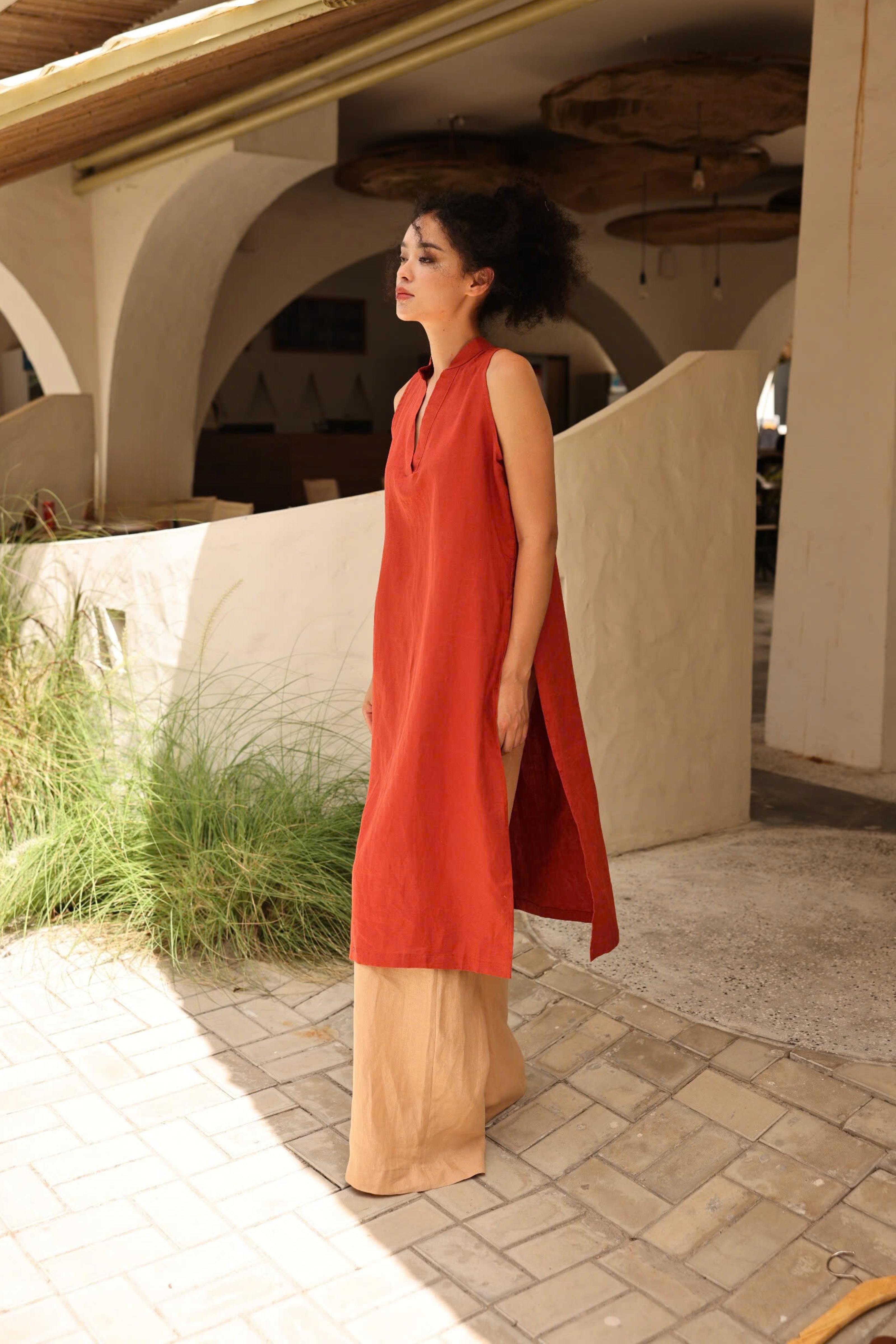 Woman in a red dress standing on a stone path with architectural elements in the background
