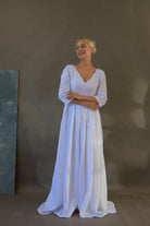 Woman wearing a white wedding dress against a plain background