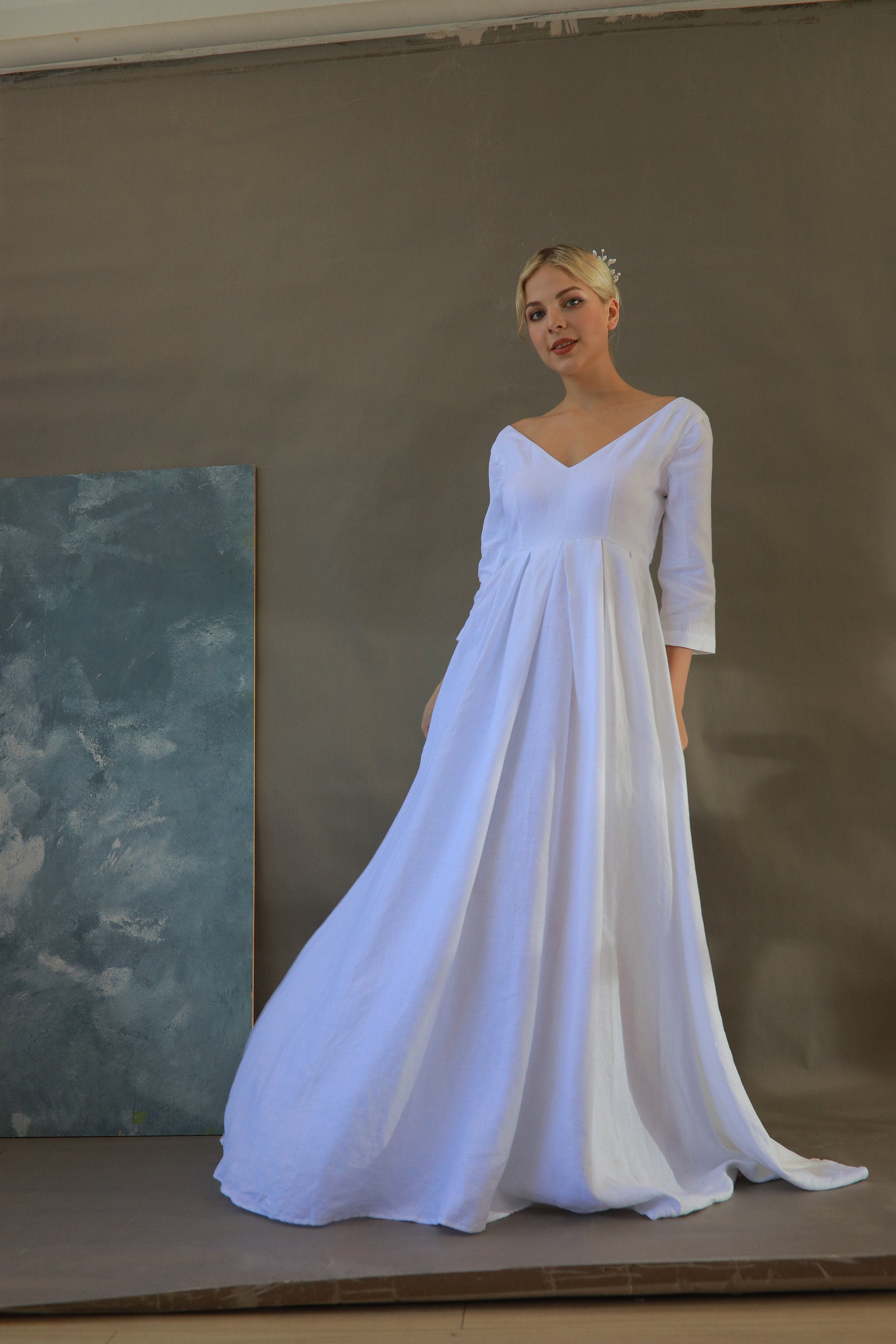 Woman wearing a white dress with 3/4 sleeves against a plain background