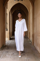 Woman in a white dress standing in an arched stone corridor