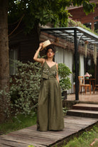 Woman in a green outfit standing on a wooden path with a rustic background