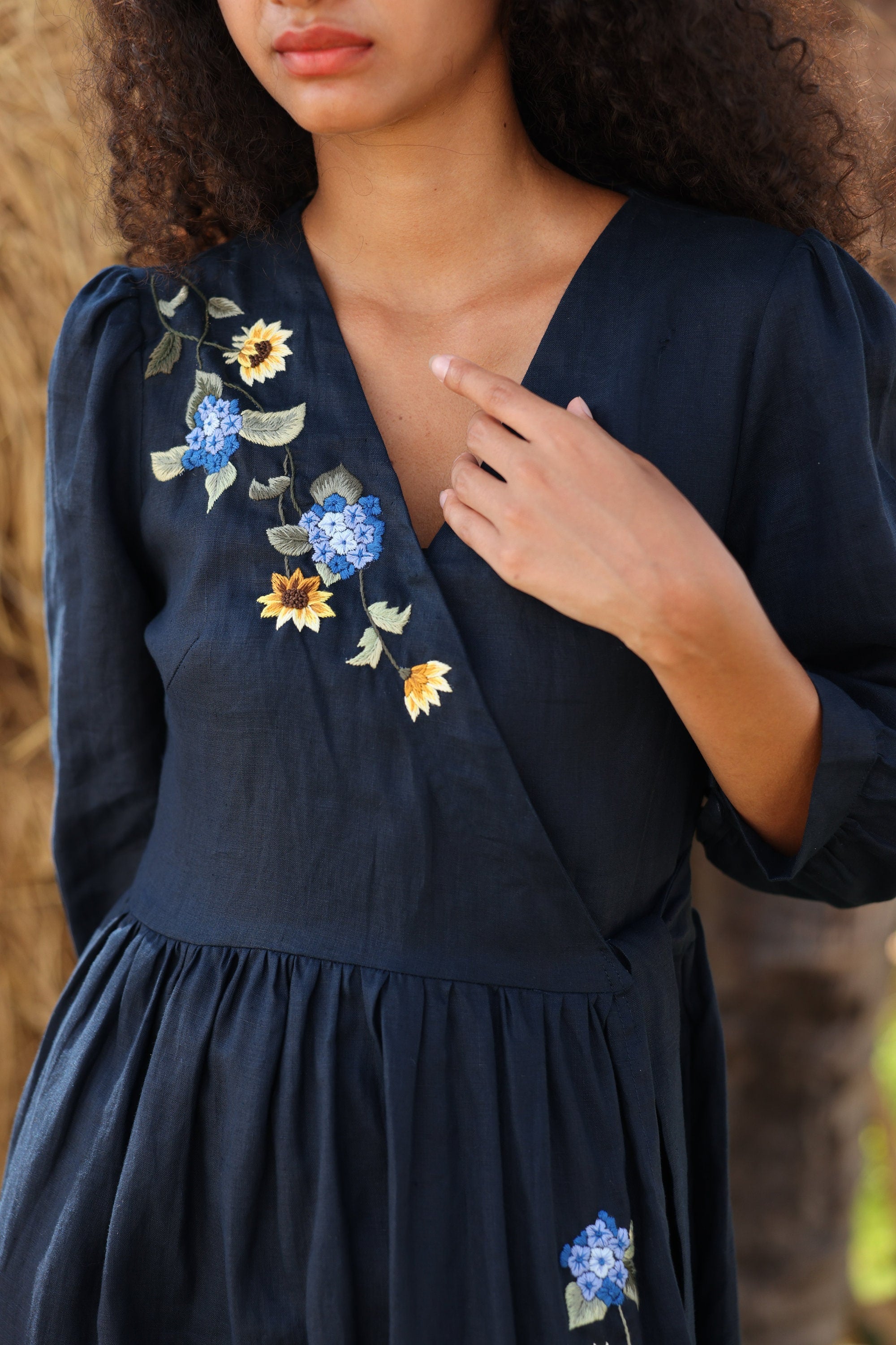 Navy blue dress with floral embroidery on a blurred natural background