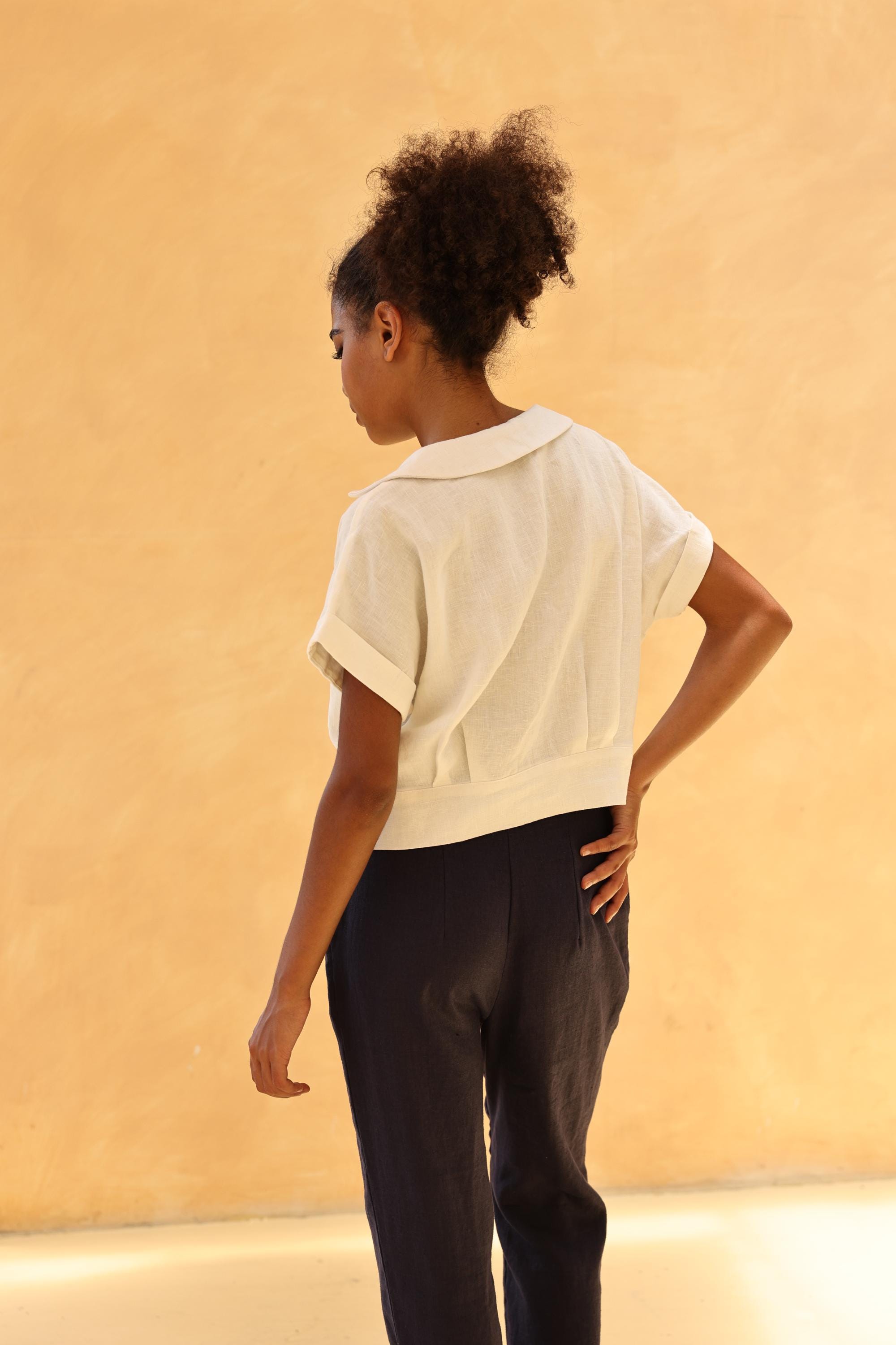 Person wearing a white short-sleeve top and pants against a beige background